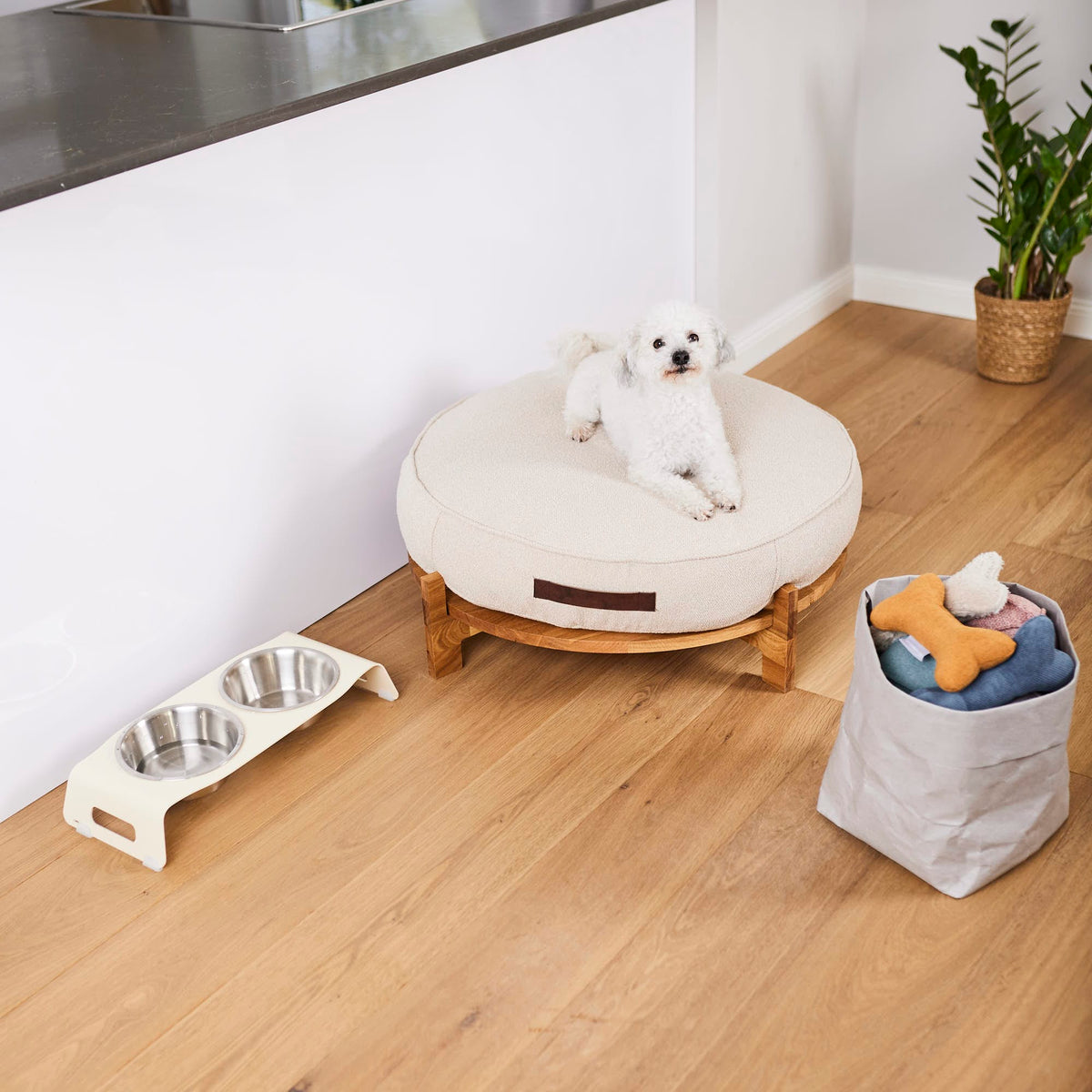 Orthopädisches Hundekissen in beige daneben Stahl Hundenäpfe und Hundespielzeug